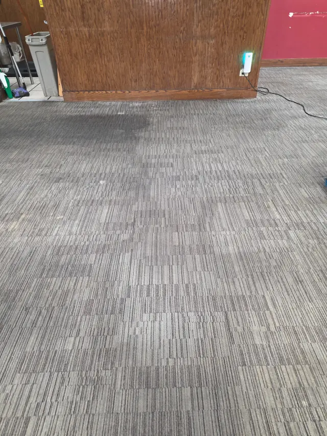 Commercial carpet tile in a restaurant dining room before cleaning, gray and dull with traffic lanes